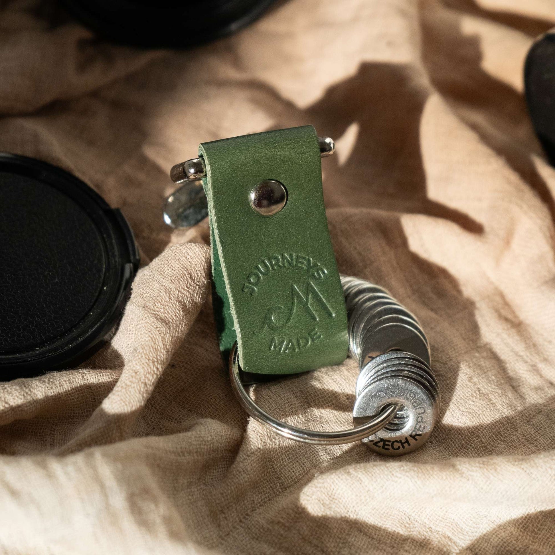 Forest green leather travel keychain featuring engraved initials, perfect for travel enthusiasts and gift giving.