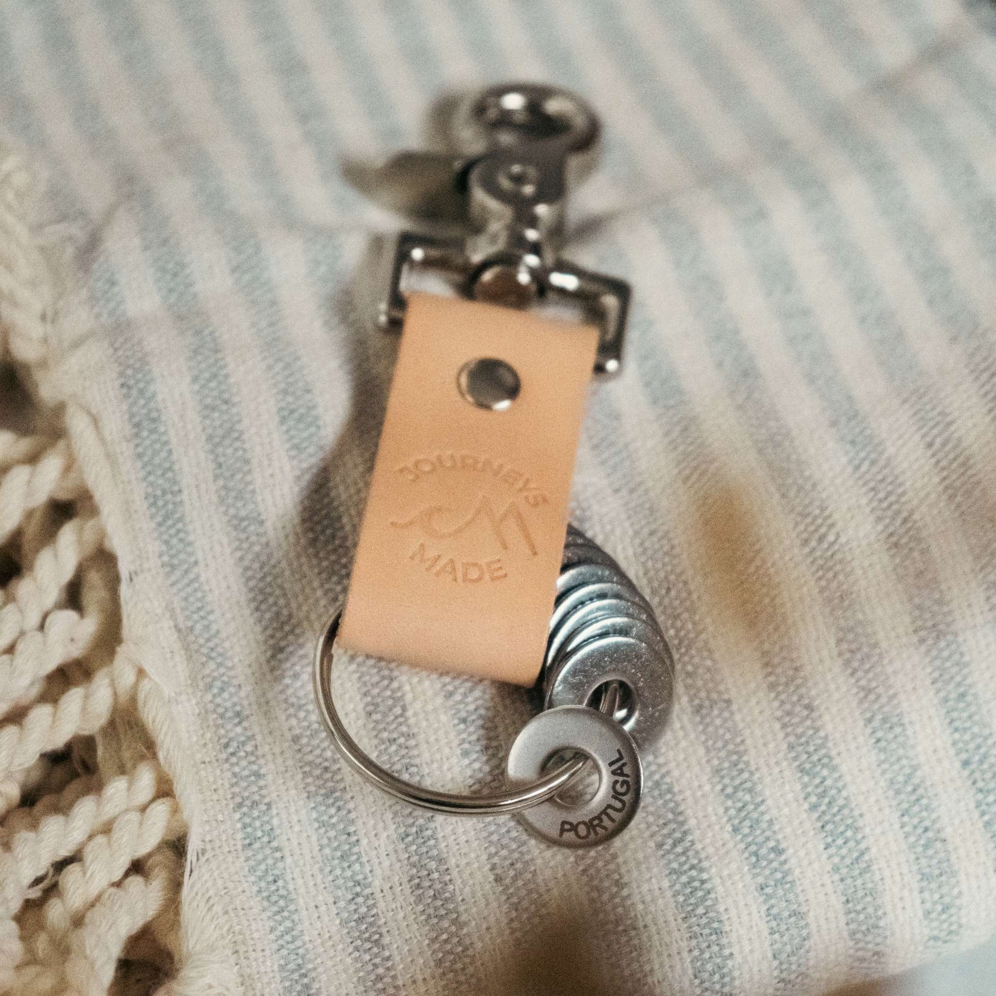 natural travel gift with leather travel keyring and engraved travel tokens on a grey and cream striped blanket