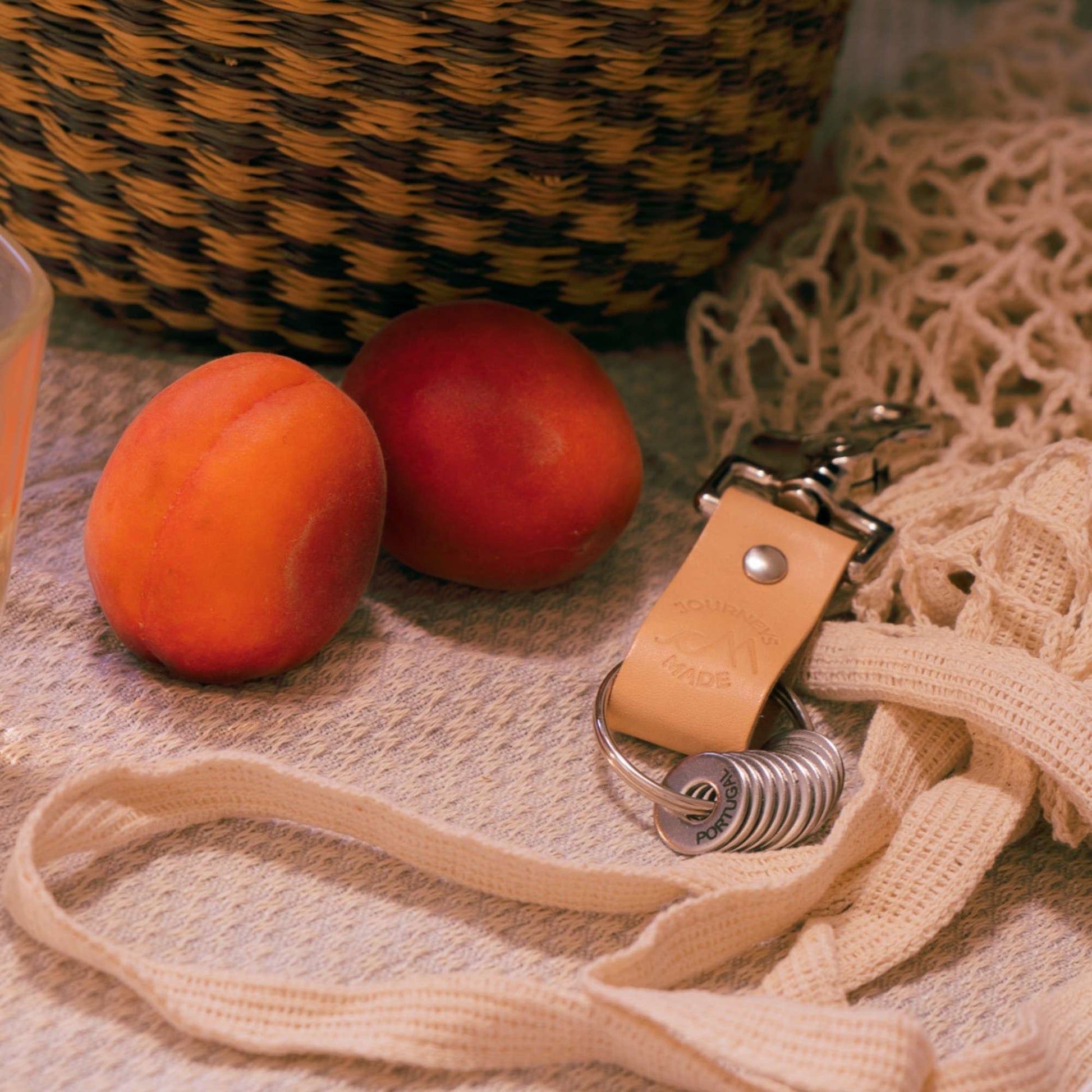 Natural leather travel keychain beside fresh apricots, styled for travel gift presentation and adventure.
