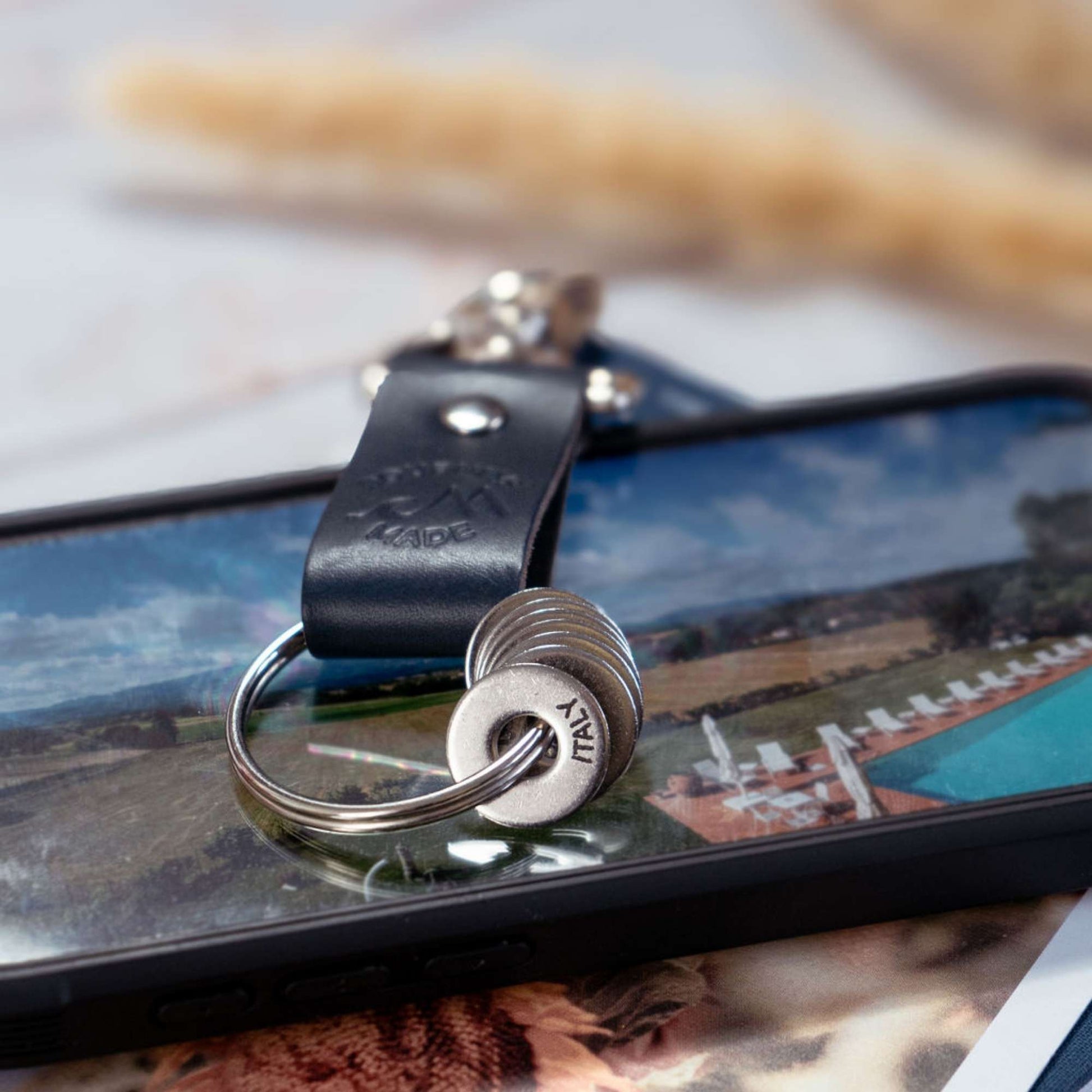 Ocean blue leather travel keyring resting on a smartphone, symbolizing cherished travel gifts and memories.