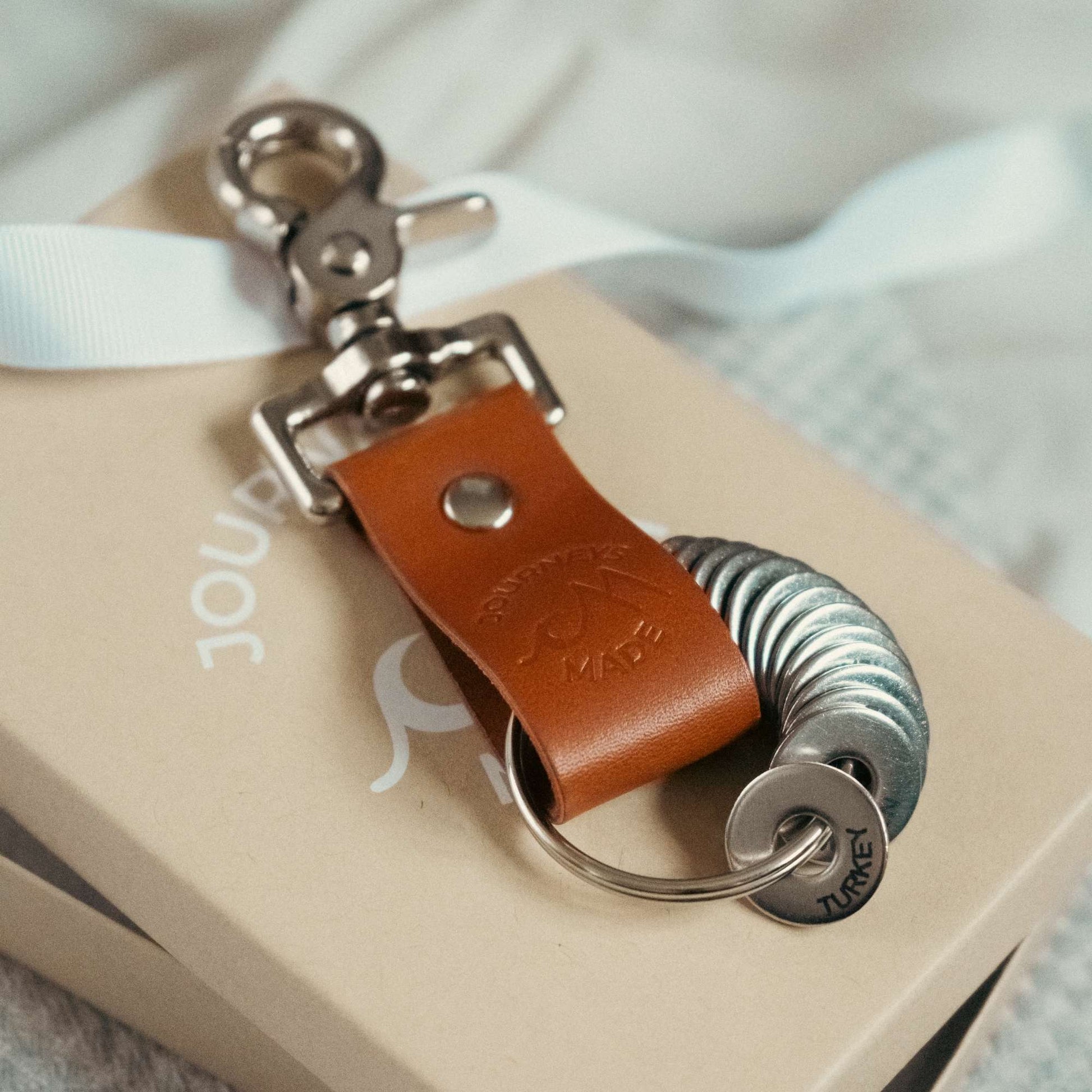 tan travel gift with leather travel keyring and engraved travel tokens on a kraft Journeys Made gift box with white ribbon on top