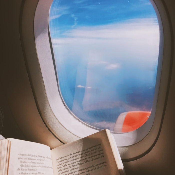 open story book next to a plane window looking out at the sea