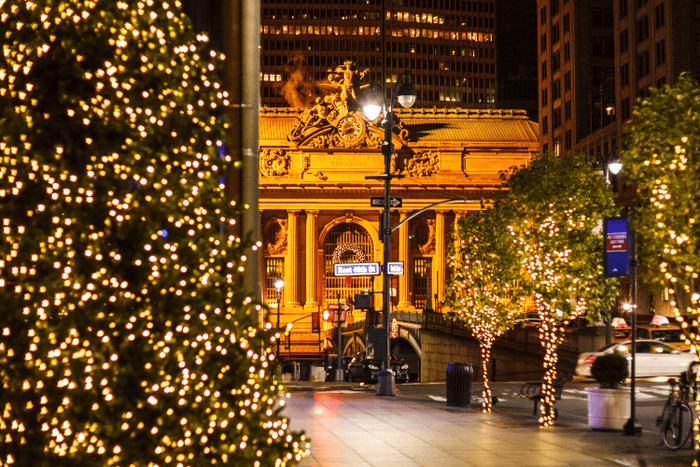 Christmas lights illuminating the streets near a grand train station, creating a festive atmosphere.