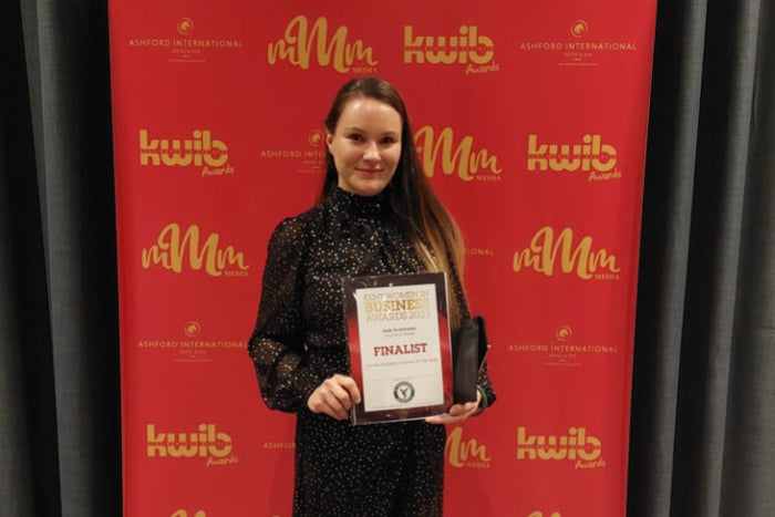 Jade Scammells founder of Journeys Made wearing a black dress with gold spots holding a Finalist for young businesswoman of the year certificate at the Kent Women in Business Awards 2023