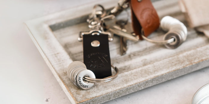 dark brown travel keychain and tan travel keychain on a white washed wooden tray with engraved travel tokens as a gift for travellers