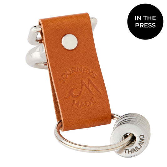 tan travel gift with leather travel keyring and engraved travel tokens on a white background with a black circle saying 'In The Press'