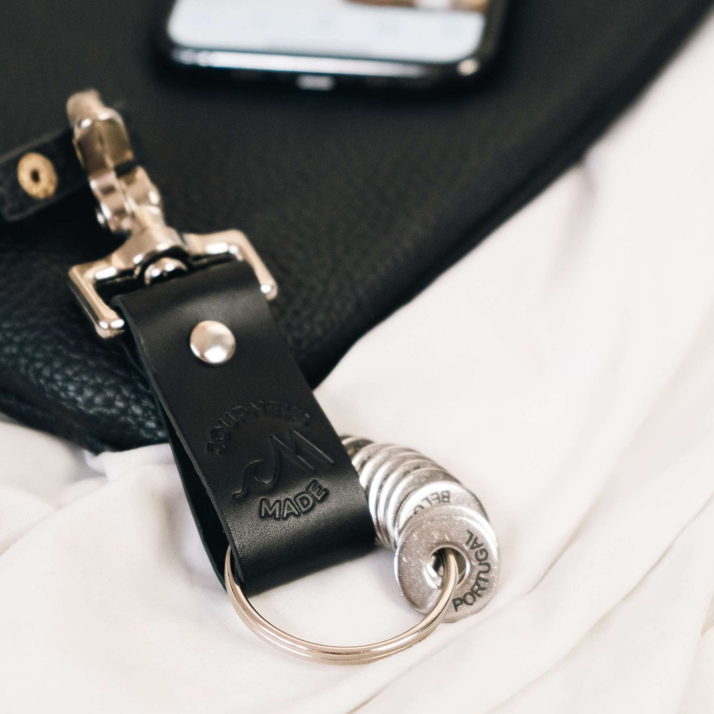 Close-up of a handcrafted black leather travel keychain attached to a travel bag, ideal for travel gift sets.