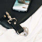 black travel gift with leather travel keyring and engraved travel tokens hooked onto a black bag with a photo showing a holiday photo in the background