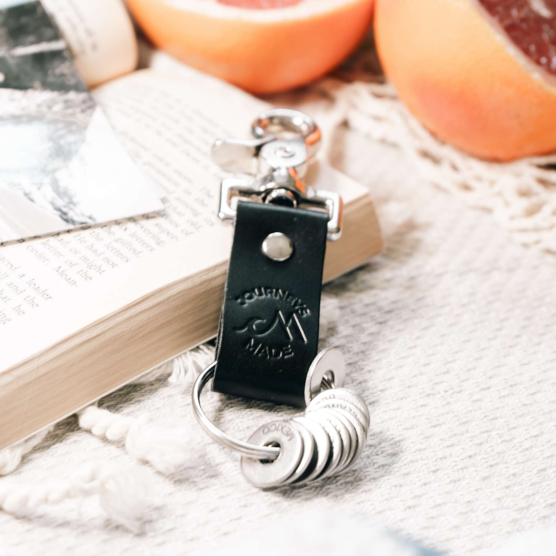 Black leather travel keyring with engraved destination tokens and silver keychain, perfect travel gift.