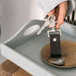 User holding a stylish travel keyring with keys, displayed on a wooden tray and plate.