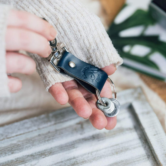 A person holds a stylish leather keyring, perfect for travel gifts and keeping keys organized.